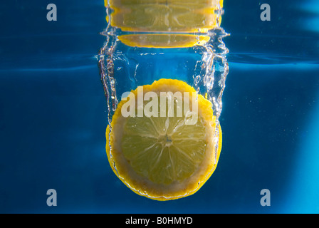 Fettina di limone cadere in acqua Foto Stock