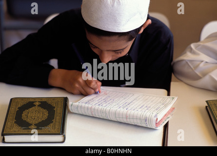 Un bambino iscritto in un libro di esercizi in aula, Arabia Saudita. Foto Stock