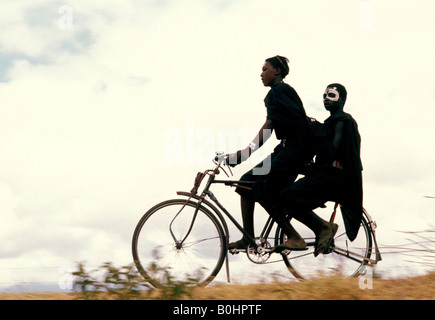 Due giovani Masai uomini in sella ad una bicicletta, Tanzania. Foto Stock