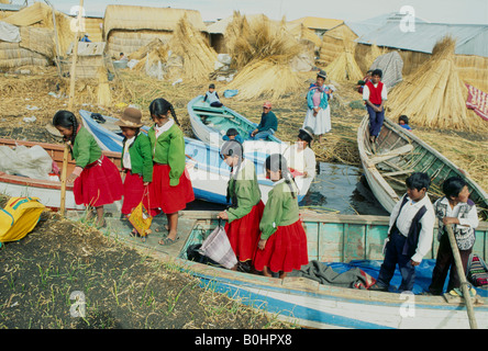 La scuola dei bambini in viaggio verso casa in barca sul lago Titicaca, Isole Uros, Perù. Foto Stock