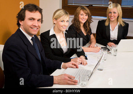 Tre dirigenti femmine ed un maschio avente una riunione in una sala riunioni il focus è il businessman in primo piano Foto Stock