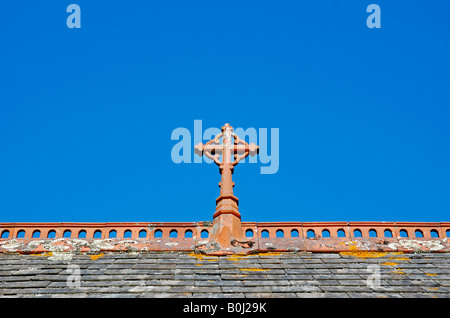 Una croce cristiana sul crinale di un tetto della chiesa Foto Stock