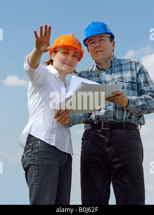 Coppia giovane che indossa caschi visualizzazione dei loro nuova casa in futuro sulla base della loro costruzione di documentazione del progetto Foto Stock