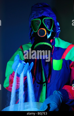 Uomo incappucciato in maschera a gas con guanti in hazmat suit vagliatura pericoloso cristalli bianchi sotto luce UV Foto Stock