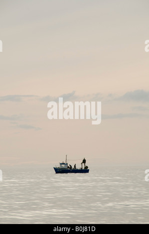Piccolo uomo due fascia costiera di pesca in barca sul mare calmo cardigan bay west wales controllo aragosta e granchio pots Foto Stock