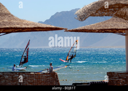 Gli appassionati di windsurf a Dahab resort per vacanze con le montagne del Sinai in distanza Mar Rosso in Egitto Foto Stock