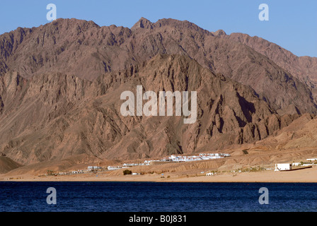 La spiaggia di Dahab resort per vacanze con le montagne del Sinai in distanza Mar Rosso in Egitto Foto Stock