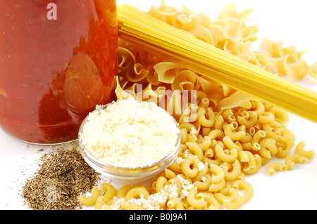 Ingredienti per la Pasta Spaghetti di noodle all'uovo di pasta tipo gramigna sugo per la pasta in un barattolo di parmigiano grattugiato isolati su sfondo bianco Foto Stock