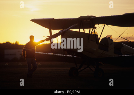 Pilot vicino ad un vecchio biplano trainer De Havilland DH 82c Tiger Moth sul tramonto Foto Stock