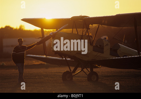 Pilot vicino ad un vecchio biplano trainer De Havilland DH 82c Tiger Moth sul tramonto Foto Stock