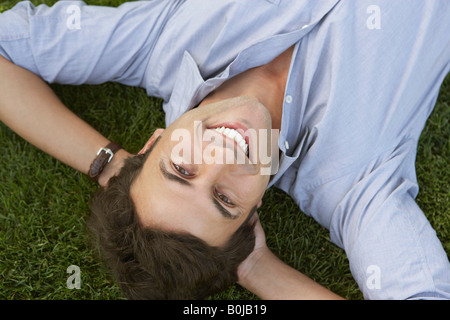 Imprenditore sorridente sdraiati sull'erba Foto Stock