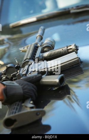 Close-up di arma di polizia sul cofano per auto Foto Stock