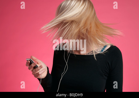 Giovane donna tenendo il lettore mp3 e lanciando i capelli Foto Stock