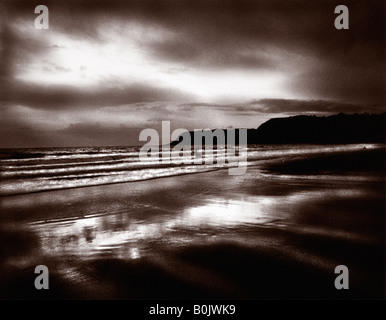 Questa è una foto della spiaggia di Caswell a Swansea sulla Penisola di Gower. Si tratta di un moody autunnale di scena con un unico surfer. Foto Stock