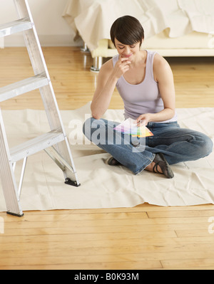 Giovane donna guardando i campioni di colore sul pavimento Foto Stock