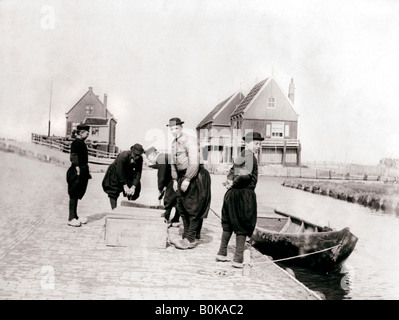 Gli uomini e i ragazzi in costume tradizionale da un canale banca, Marken Isola, Olanda, 1898. Artista: James Batkin Foto Stock