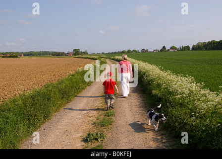 Madre e Figlio passeggiate con il cane lungo un Paese via Foto Stock