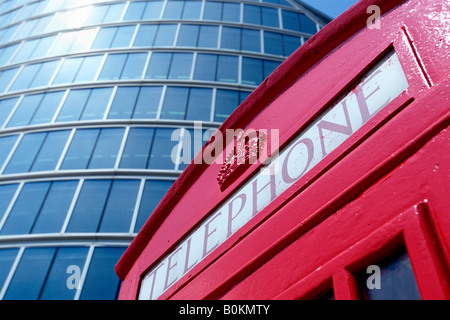Un tradizionale telefono rosso scatola con vetro moderno edificio per uffici in background Foto Stock