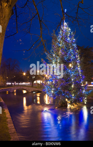 Un albero di Natale nel centro del Fiume Windrush nel villaggio Costwold di Bourton sull'acqua, Gloucestershire Foto Stock