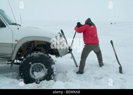 L uomo come ottenere un 'superjeep' al di fuori di un foro nel ghiacciaio Langjokull, Islanda. Foto Stock