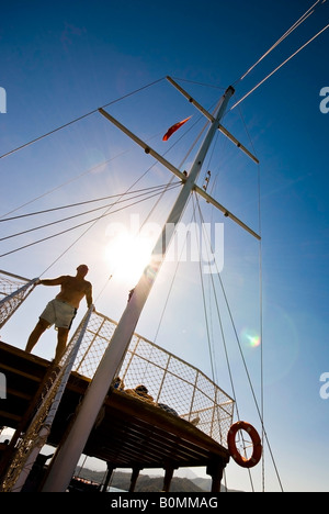 Montante di sollevamento di una barca e di un uomo contro la luminosa blu cielo con il sole attraverso clamorose. Dodici isole tour in FETHIYE Turchia. Attività vacanze vicino Olu Deniz. Foto Stock