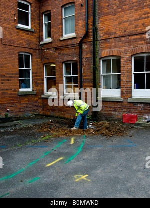 I lavori di costruzione - Operaio edile in elmetto e hi viz camicia di scavare un buco nel terreno. Foto Stock