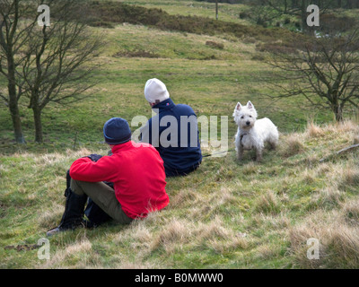 Giovane seduto e appoggiato con il loro cane, sul Mam Tor. Parco Nazionale di Peak District. Derbyshire Foto Stock