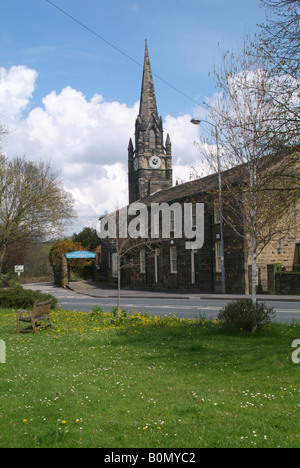 Il campanile della chiesa parrocchiale di Santa Maria Nascente al di là di case terrazza in Main Street Burley in Wharfedale Foto Stock