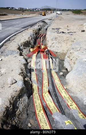 Esposti i cavi di alimentazione in trincea stradale nastri di avvertimento nella massa di attenzione i cavi Eelectric Foto Stock