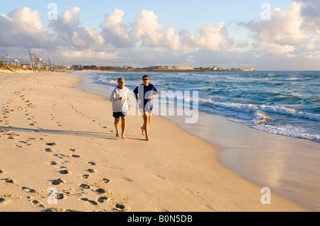 Due uomini insieme per fare jogging sulla spiaggia nel sole del tardo pomeriggio. Leighton Beach. Foto Stock