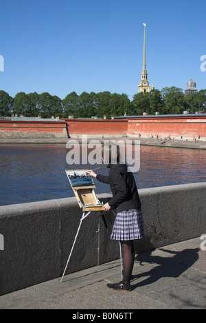 Femmina giovane artista di strada dipingere un quadro a San Pietroburgo, Russia. Il Pietro e Paolo Rocca e la cattedrale possono anche essere visto Foto Stock