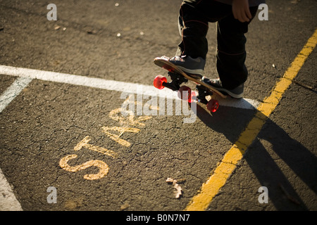 6 anno vecchio ragazzo gioca con il suo nuovo skateboard per la prima volta Foto Stock