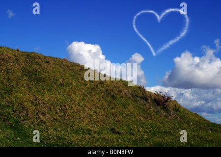 Amore cuore nel cielo fatte da un aereo su una verde collina montagna Foto Stock