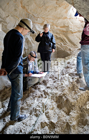 Persone per misurare la lunghezza mentre esplorate la grotta presso Vaidavas hillfort in Gauja Parco Nazionale della Lettonia Foto Stock