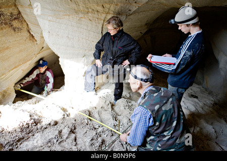 Persone per misurare la lunghezza mentre esplorate la grotta presso Vaidavas hillfort in Gauja Parco Nazionale della Lettonia Foto Stock