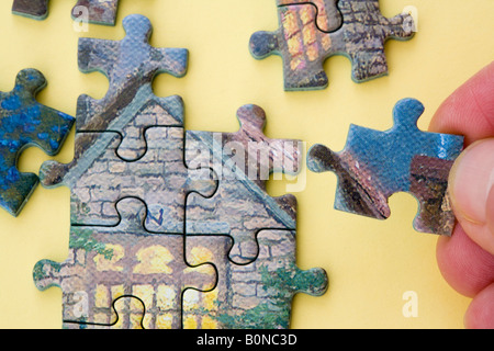 Puzzle close up della persona adulta facendo una foto puzzle tenendo un pezzo del puzzle. Foto Stock