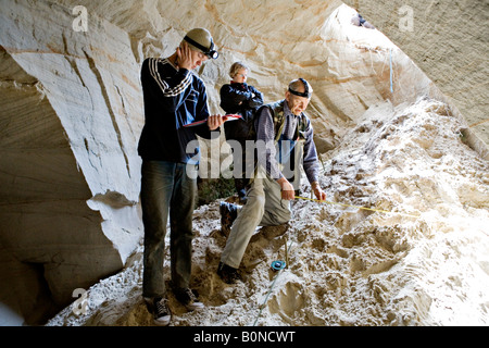 Persone per misurare la lunghezza mentre esplorate la grotta presso Vaidavas hillfort in Gauja Parco Nazionale della Lettonia Foto Stock