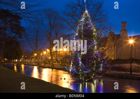 Un albero di Natale nel mezzo del fiume Windrush nel villaggio Cotswold di Bourton on the Water, Gloucestershire, Regno Unito Foto Stock