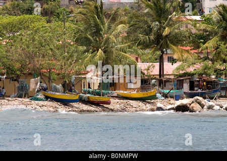 Barche di pescatori sulla spiaggia con i pescatori riassettavano le reti sotto gli alberi in Anse La Raye, Saint Lucia, dei Caraibi Foto Stock