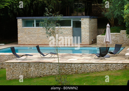 Un giardino piscina affiancata da una pietra di Cotswold spogliatoio con malta di calce e puntamento stalattite pareti di ritegno REGNO UNITO Foto Stock