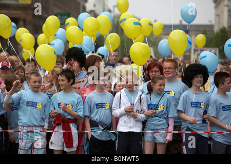 La folla di bambini concorrenti con palloncini linea fino alla linea di partenza della maratona di Belfast fun run 2008 Belfast City Centre Foto Stock