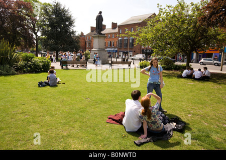 Regno Unito Inghilterra Lincolnshire Grantham St Peters Hill la gente seduta su erba in sun vicino a Isaac Newton statua Foto Stock