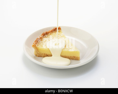 Fetta di tarte au citron, con colata di crema di latte Foto Stock