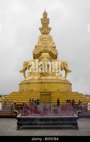 Statua di sfaccettata Buddha seduto sulla sommità del sei-tusked elefanti con davanti i credenti portando offerte di incenso Foto Stock