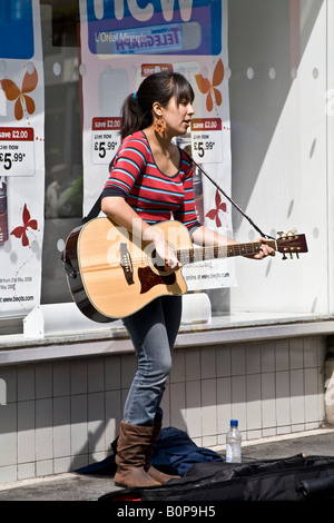 Sarah Coloso giocando gypsy swing pre-rock sulla sua chitarra acustica a fianco di vetrine a Dundee, Regno Unito Foto Stock
