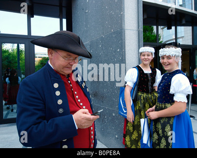 Uomo in costume storico tramite cellulare telefono cellulare con due ragazze ridere il Parlamento europeo Bruxelles Belgio Foto Stock