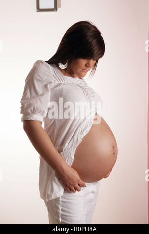 36 settimana incinta Donna adolescente guardando il suo esposto lo stomaco . Foto Stock