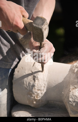 Stone Mason carving una colonna circolare con un martello e uno scalpello Foto Stock