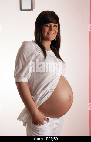 36 settimana incinta Donna adolescente mostrando il suo stomaco esposta Foto Stock