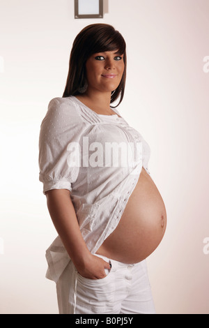 36 settimana incinta Donna adolescente mostrando il suo stomaco esposta Foto Stock